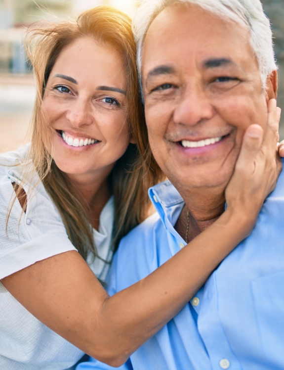 Senior couple hugging and smiling with All on 4 dental implants in Succasunna