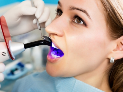 Woman receiving cosmetic dental bonding treatment on upper front tooth
