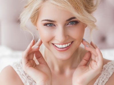 Smiling blonde woman framing her face with her hands