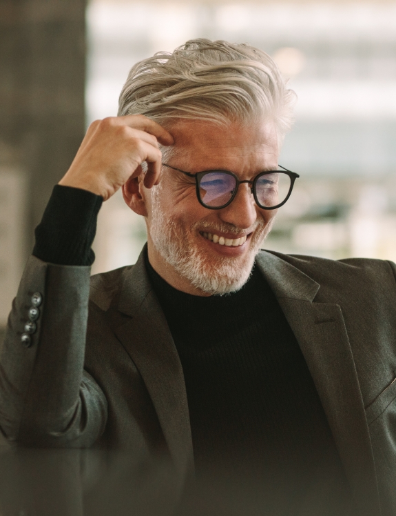 Senior man in black suit smiling with dental bridges in Succasunna