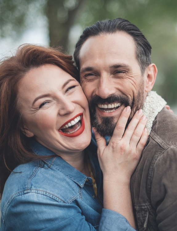 Man and woman holding each other and smiling with dental crowns in Succasunna
