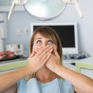Woman covering her mouth in fear in the dental chair