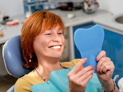 Senior woman at the dentist’s looking at her teeth in a mirror