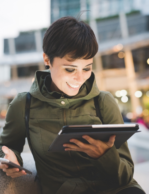 Woman smiling while looking at her tablet