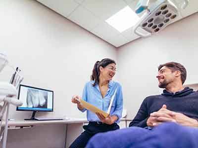 Smiling patient and dentist reviewing X-ray