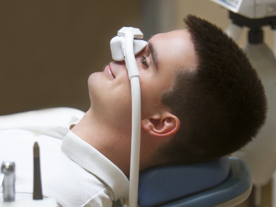 Man laying down in dental chair with nitrous oxide mask over his nose