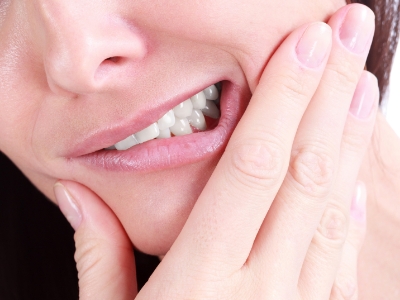 Close up of person wincing and holding their jaw in pain