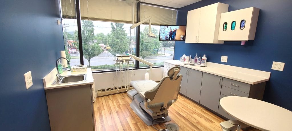 Dental treatment room with large window showing parking lot