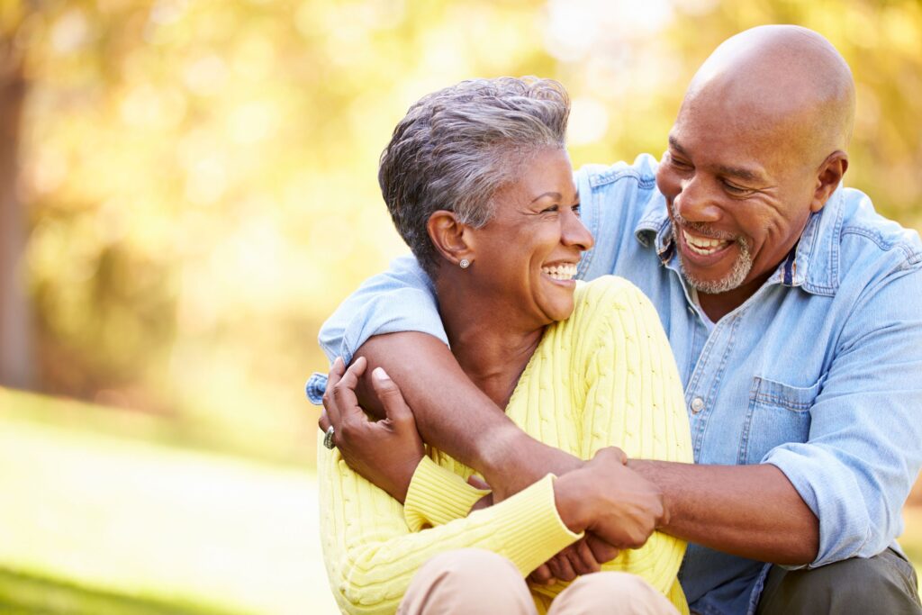 Man in blue shirt hugging woman in yellow sweater from behind